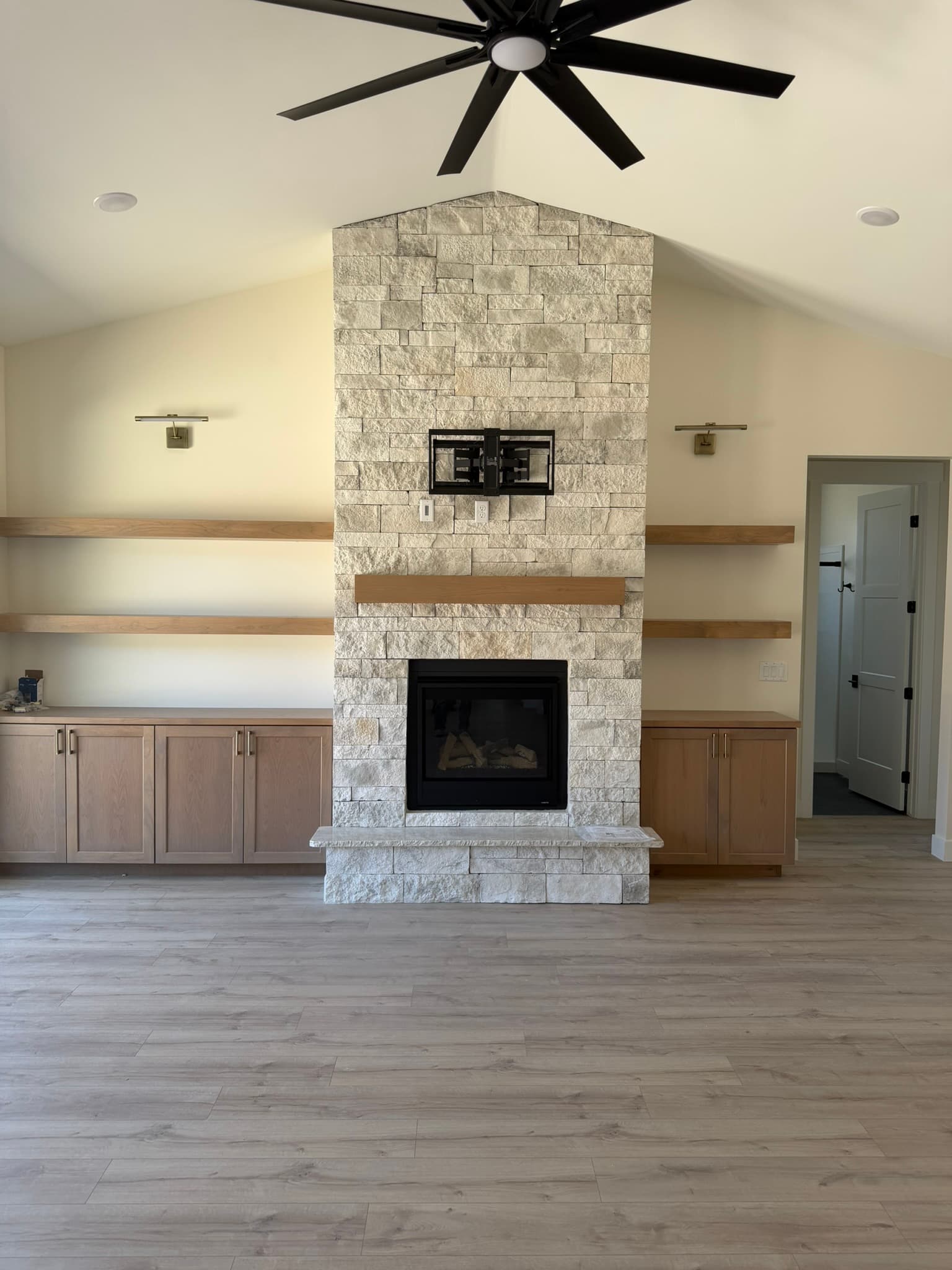 Stone fireplace with floating shelves and custom cabinetry